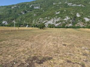 an empty field with a fence and a mountain at Willage camp i auto camp KOMARNICA in Šavnik