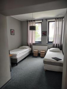 ein Schlafzimmer mit zwei Betten und zwei Fenstern in der Unterkunft Hotel Wołów in Wołów