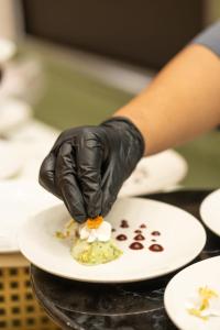 a person in black gloves holding a plate of food at Kiwa Banquet & Hotel in Koba
