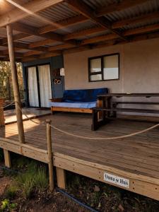 a porch with a bed and a wooden deck at 11 Mountain Stream Hot Tub Self Catering in Gordonʼs Bay