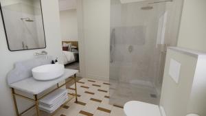 a white bathroom with a sink and a shower at Eendracht Hotel in Stellenbosch