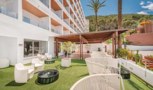 an outdoor patio with white chairs and grass at Palladium Hotel Cala Llonga - Adults Only in Cala Llonga