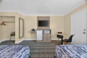 a hotel room with two beds and a refrigerator and a table at Seaside Inn Monterey in Seaside