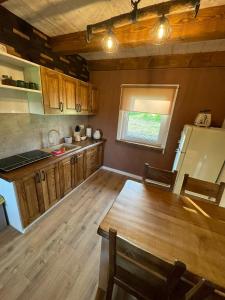 a kitchen with wooden cabinets and a table and a window at Domki BIERWIONO in Cisna
