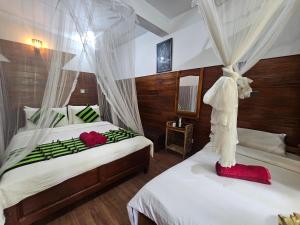 a bedroom with two beds with white and red sheets at MUM Jungle Inn in Ella