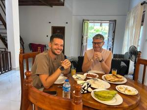 two men sitting at a table eating food at Diyathna Nuwarawewa in Anuradhapura