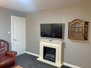 a living room with a fireplace with a flat screen tv at Pinecote in Bottesford