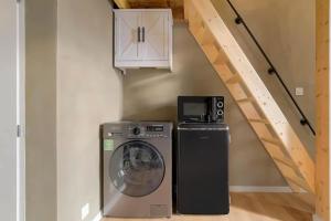 a washing machine and a microwave next to a staircase at Lyon Cité Internationale - Loft Industriel Neuf in Caluire-et-Cuire