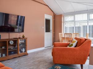 a living room with an orange chair and a flat screen tv at Pinecote in Bottesford
