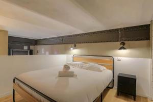 a bedroom with a bed with white sheets and a book on it at Lyon Cité Internationale - Loft Industriel Neuf in Caluire-et-Cuire
