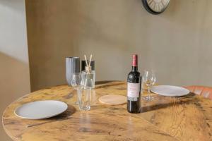 a bottle of wine sitting on a wooden table with glasses at Lyon Cité Internationale - Loft Industriel Neuf in Caluire-et-Cuire