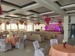 a banquet hall with tables and chairs and a stage at Hotel Vasant - Premium Hotel in Gajraula - All AC Rooms with Restaurant - Free Wi-fi & Parking - Banquet in Gajraula