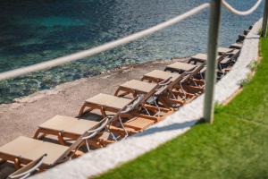 a row of chairs sitting next to the water at Palladium Hotel Cala Llonga - Adults Only in Cala Llonga