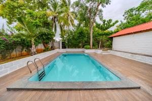 a swimming pool in a yard with a wooden floor at Aavaranaa Farmstay in Kanakapura
