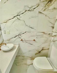 a bathroom with a white toilet and a marble wall at Premium House in Comodoro Rivadavia