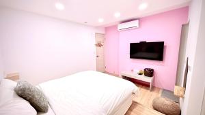 a bedroom with a white bed and a pink wall at 小邱民宿 in Anping