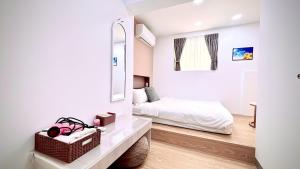 a white bedroom with a bed and a mirror at 小邱民宿 in Anping