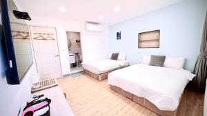 a bedroom with two beds and a desk with a laptop at 小邱民宿 in Anping +8 photos