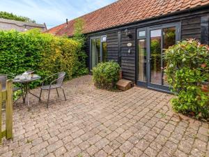 a patio with a table and chairs in front of a house at Thyme - E4485 in Catfield +2 photos