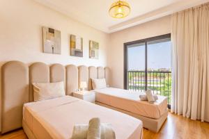 two beds in a room with a large window at Appartement Noria Golf in El Makina +23 photos
