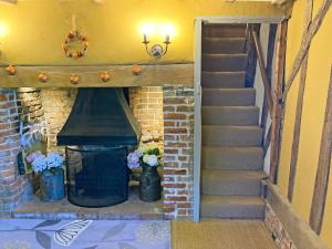 a staircase leading to a fireplace with vases of flowers at Bell Corner Cottage in Cratfield