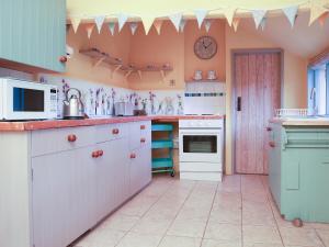a kitchen with a counter with a microwave and a stove at Bell Corner Cottage in Cratfield +11 photos