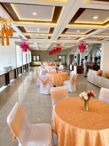 a banquet hall with white tables and white chairs at Hotel Vasant - Premium Hotel in Gajraula - All AC Rooms with Restaurant - Free Wi-fi & Parking - Banquet in Gajraula