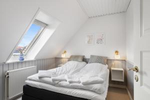 a bed with white sheets in a room with a window at Løkken Badehotel Apartments in Løkken +63 photos
