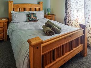 a bedroom with a wooden bed with two pillows at Park Lodge in Strachan