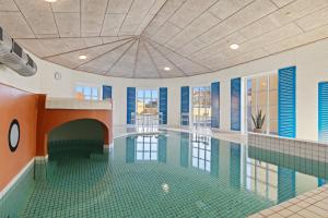 an indoor swimming pool with a tile floor and a ceiling at Løkken Badehotel Apartments in Løkken