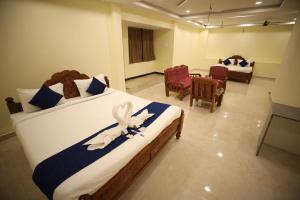 a bedroom with two beds with chairs and a table at StarlightHotels ARResidency in Chennai