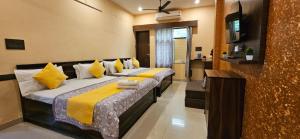 a bedroom with two beds with yellow and white pillows at Krishna's land Homestay in Vrindāvan