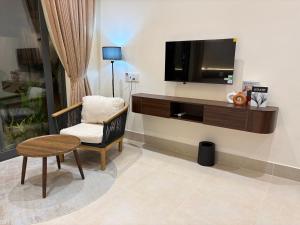 a living room with a tv and a chair and a table at Samphia Homestay in Nguyệt Hòa