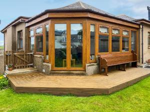 a gazebo with a bench on a wooden deck at Maple Cottage in Inverallochy