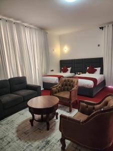 a hotel room with two beds and a couch and a table at GRANADA HOTEL NAIROBi in Nairobi