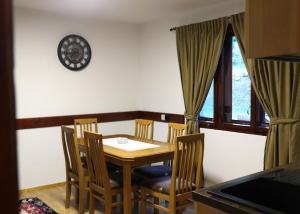a dining room table with chairs and a clock on the wall at FoRest Apartment in Mokra Gora +16 photos