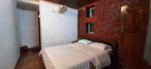a small bedroom with a white bed and a red wall at Leela Villa - Ancient Redstone Escape in Panchgani
