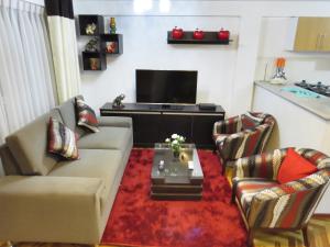 a living room with a couch and chairs and a tv at Apartamentos Quewe in Cusco