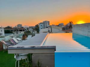 a pool on the roof of a building with the sunset at Lokàl Boutique Hotel in Larnaca