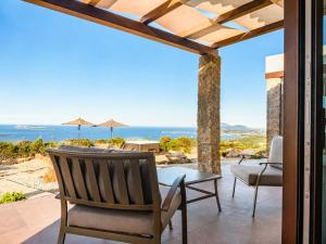 a patio with a table and chairs and a view of the ocean at Villa Ottavio Costa Smeralda View 360 in San Pantaleo