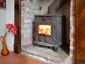 a wood stove in a room with a fireplace at Wee Dug Hoose in Glenluce