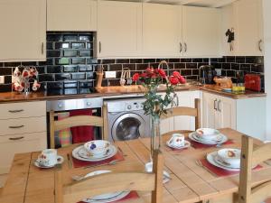 a kitchen with a table with a vase of flowers at Wee Dug Hoose in Glenluce
