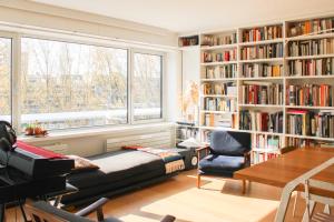 a living room with a bed and bookshelves at Spacious cocoon with a terrace view on the canal in Paris +35 photos