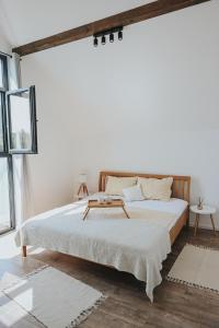 a white bedroom with a bed with a wooden headboard at Vikendica Family in Gojsalica