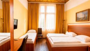 a bedroom with two beds and a desk and a window at Hotel AI Königshof in Berlin