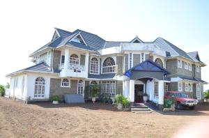 a large house with a red car parked in front of it at Balmoral Palace Kisumu in Kisumu International Airport