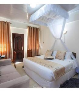 a white bedroom with a large bed and a couch at Balmoral Palace Kisumu in Kisumu International Airport