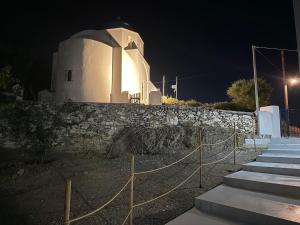 a white church at night with a stone wall at Nion Stays in Katapola +1 photo