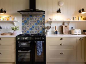 a kitchen with a black stove and white cabinets at Costers Lodge in Midhurst +20 photos