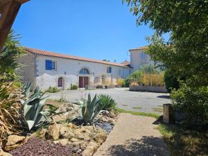 a house with a yard with some plants in front of it at Chambres d'hôtes -- Le Clos de Gémozac in Gémozac